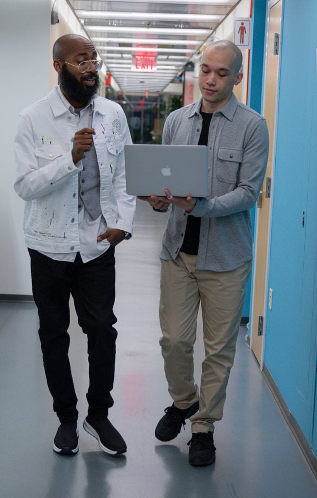 Resilient Coders talking in hall with laptop